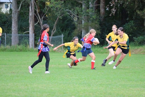 Five female students on a field playing football.